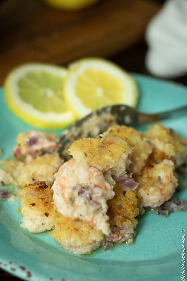 close up of crunchy baked shrimp on blue plate with lemon wedges