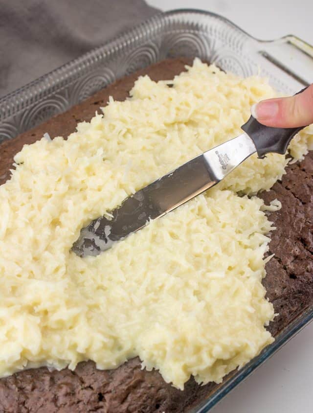 creamy coconut mixture spread on chocolate cake