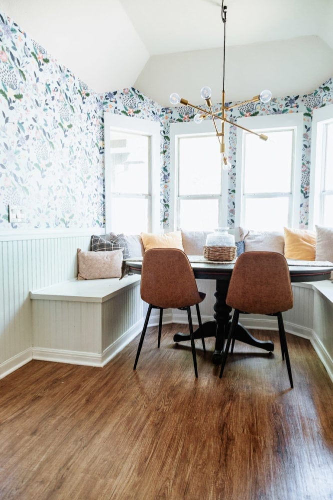 a dining room with floral wallpaper and a built-in bench