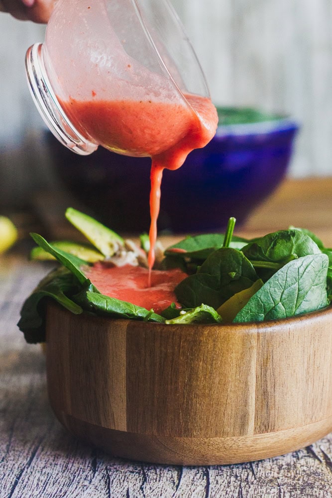 strawberry lemon vinaigrette being poured over keto chicken avocado salad