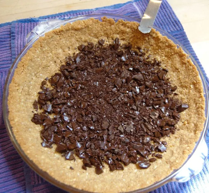 Sprinkle the chopped chocolate onto the hot crust and allow it to melt before spreading it over the entire crust.