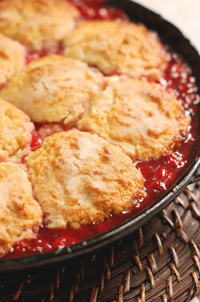 a closeup shot of a cherry cobbler in a cast iron skillet
