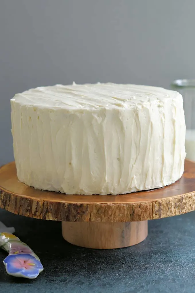 a vanilla iced cake on a cake stand