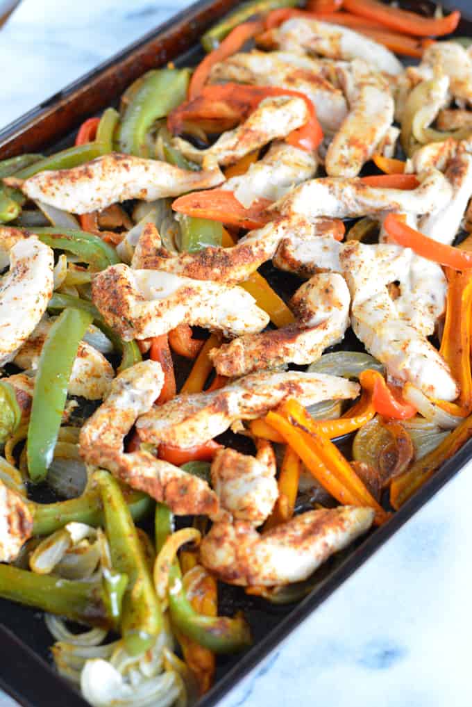 Chicken fajita mixture on top of a baking sheet.