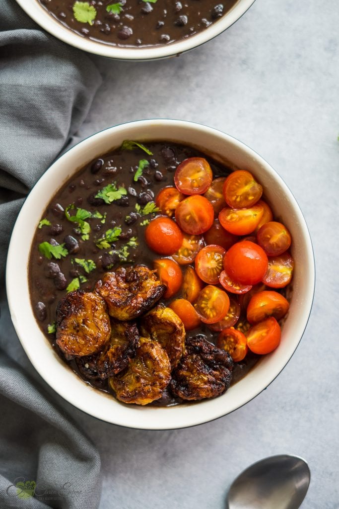a serving of air fryer plantains with instant pot cuban black beans and some cherry tomatoes sprinkle with fresh cilantro.