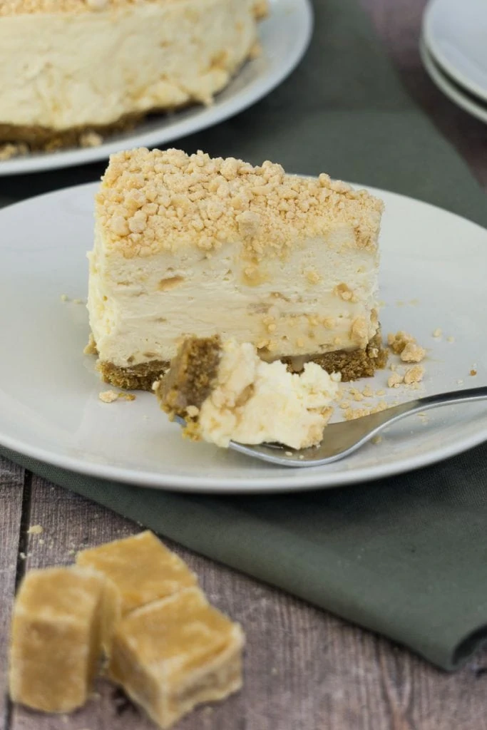 Slice of Scottish Tablet Cheesecake recipe on a plate with fork and bite taken out of it