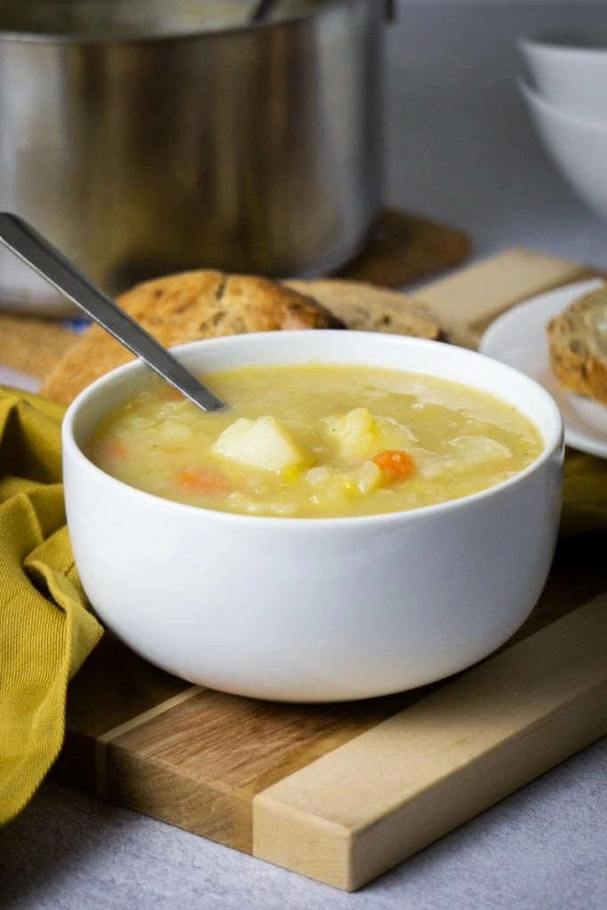 Scottish Potato Soup and Tattie Soup Recipe in a bowl with bread and potatoes beside