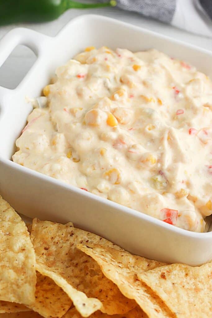This Cheesy Slow Cooker Fiesta Corn Dip is a creamy, cheesy dip recipe that's perfect for any party. It's great for tailgating, too!