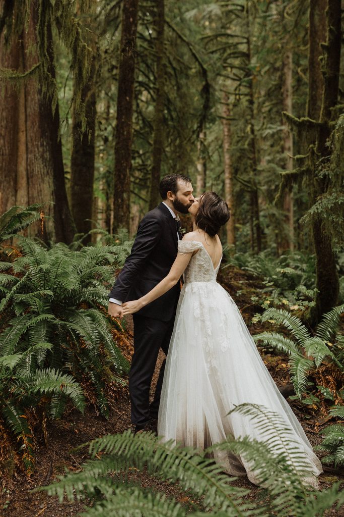 A newlywed couple kiss while standing in the woods of Olympic National Park during their elopement photographed by Alexa Ann Photography