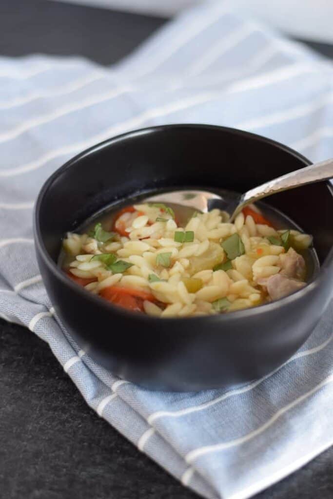 Ninja Foodi chicken soup in a black bowl with blue and white tea towel