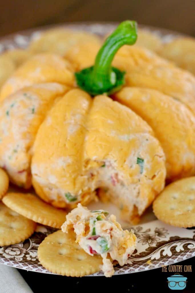 Vegetable Cream Cheese Cheeseball covered in shredded cheddat cheese and shaped into a pumpkin