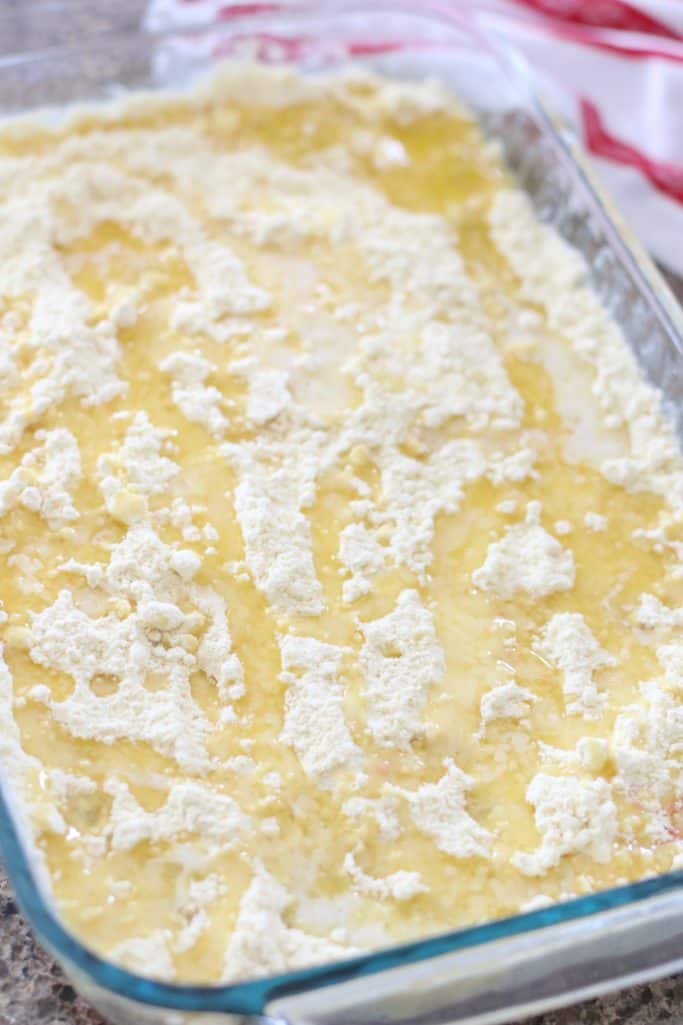 melted salted butter spread on yellow cake mix on top of cherry pie filling in a glass baking dish