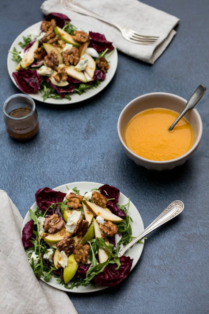 pear gorgonzola salad on two salad plates with bowl of butternut squash soup