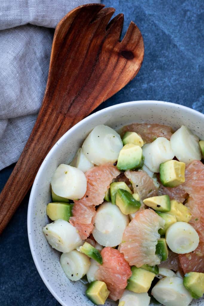 close up of hearts of palm salad with avocado with spoon and towel