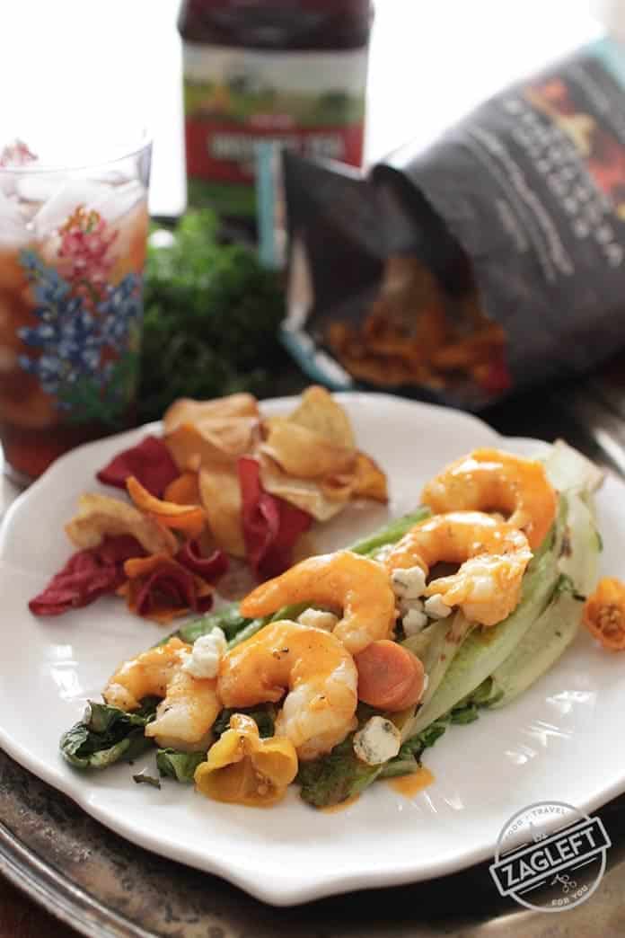 Grilled Buffalo Shrimp served over grilled Romaine Lettuce and topped with blue cheese crumbles plated with chips