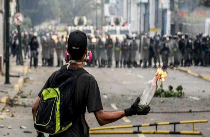 Muchos leen y escuchan refranes, sin aprender el mensaje. En la foto se observa a un manifestante enfrentando a las fuerzas policiales y militares de Venezuela.