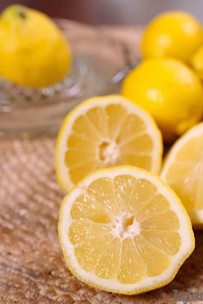 Close up of two lemon halves and whole lemons behind them out of focus