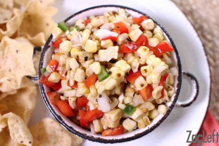 An overhead view of a bowl of corn salsa plated with tortilla chips
