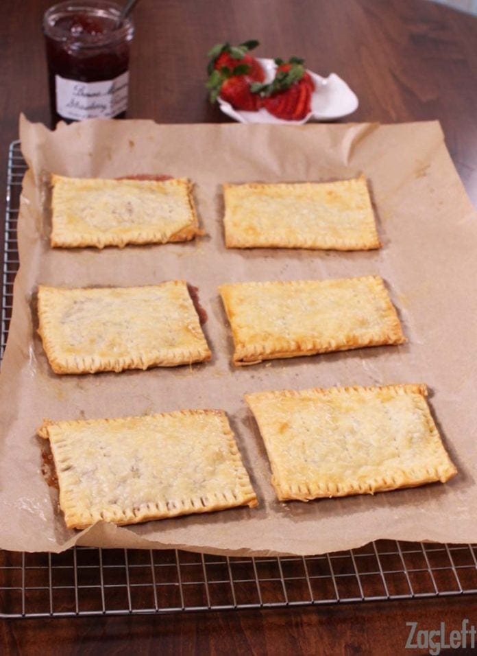 Six homemade toaster pastries on parchment paper on a cooling rack