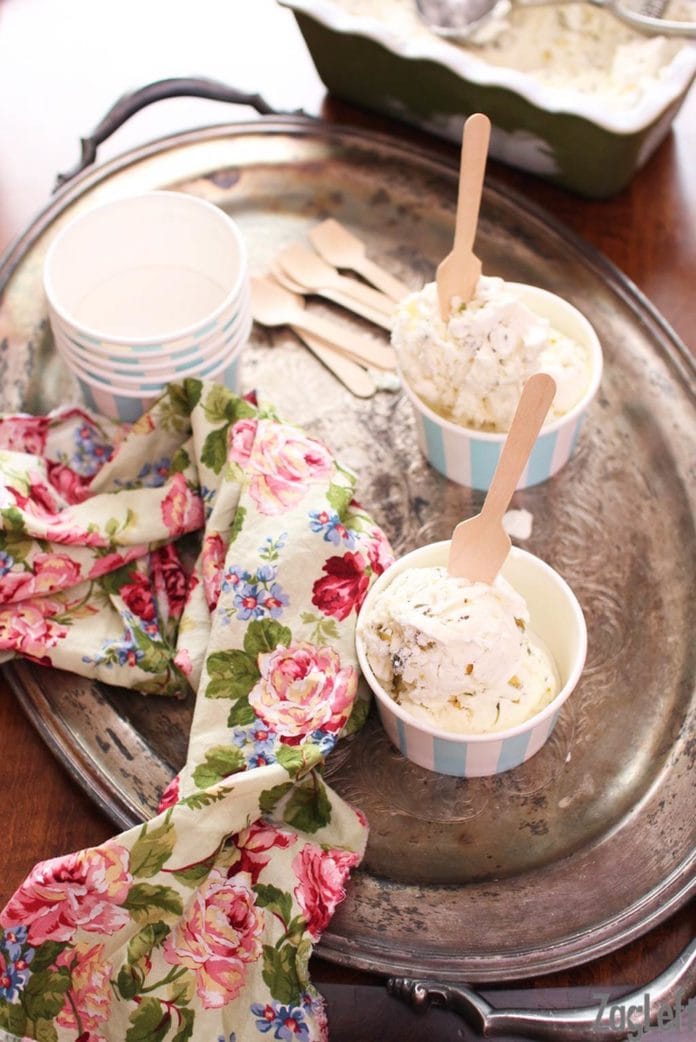 Overhead view of two bowls of Pistachio Ice Cream with wooden ice cream spoons on a metal tray next to a floral napkin