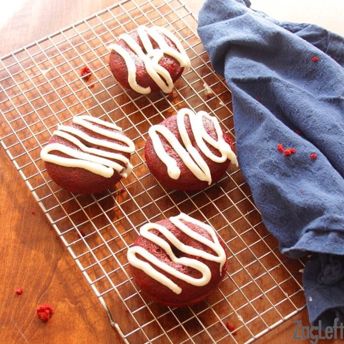 four donuts on a cooling rack on top of a brown table with a blue napkin draped across the rack.