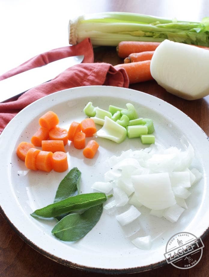 A small plate of chopped ingredients in dressing- carrots, celery, onions, and sage leaves