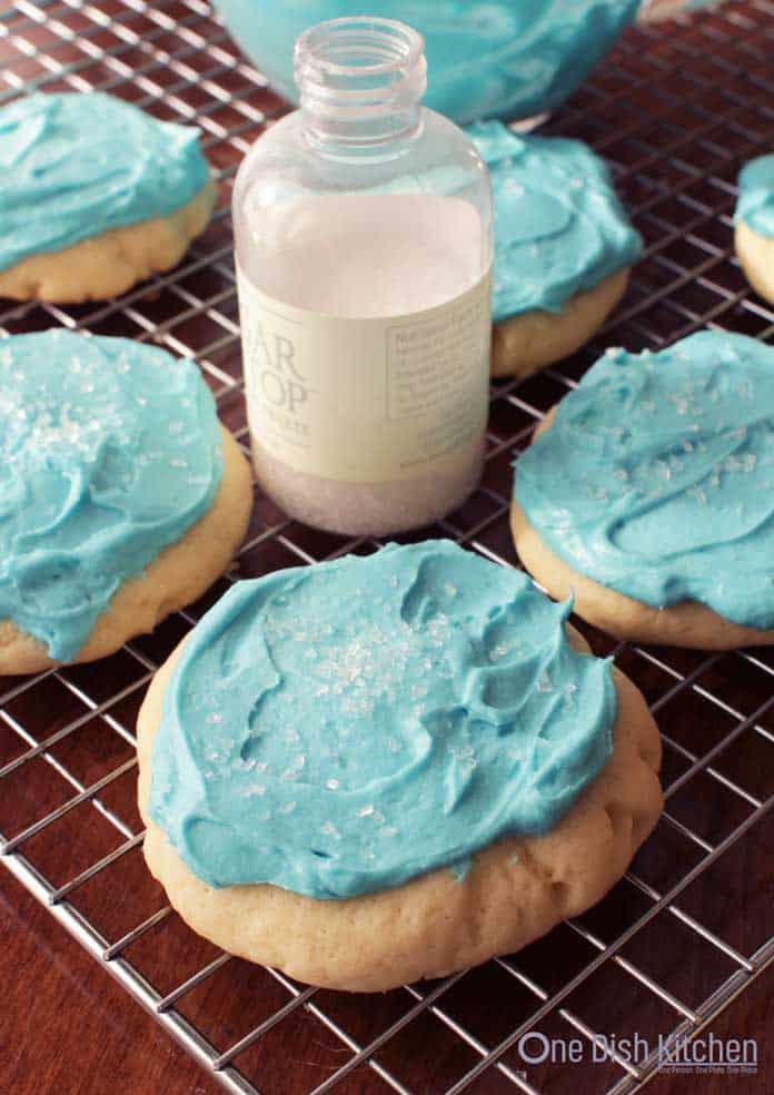 Blue Frosted Lofthouse Sugar Cookies with white crystal sprinkles on a cooling rack