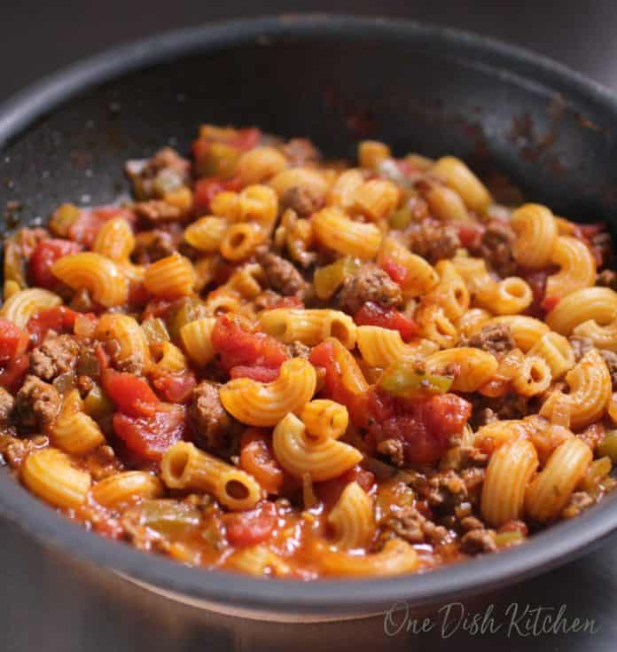 goulash cooking in a pan filled with ground beef, noodles, and tomato sauce | one dish kitchen