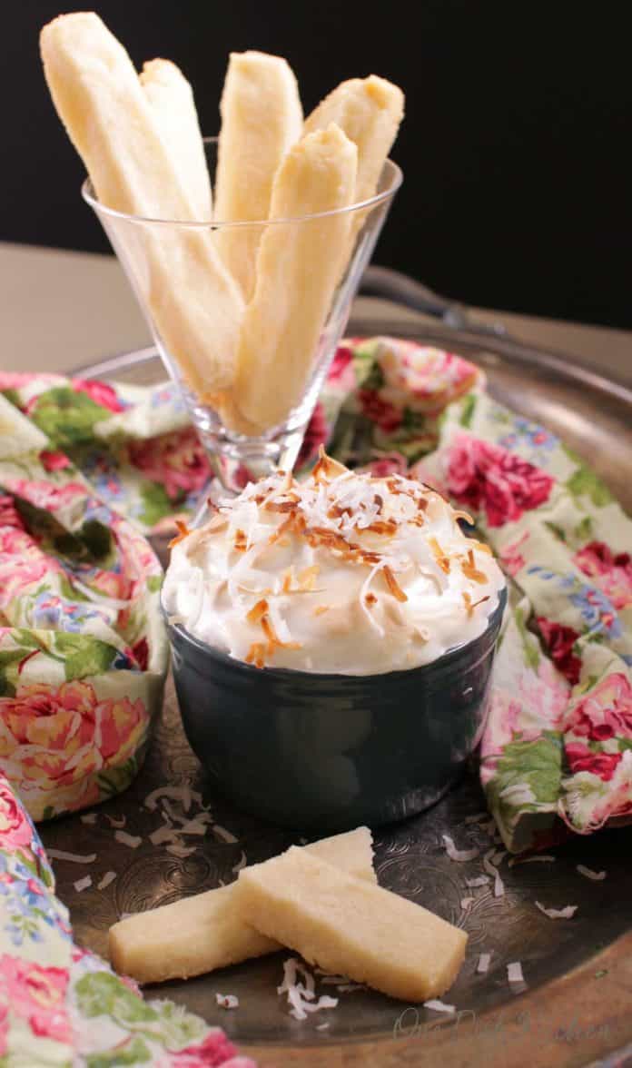 one coconut cream pie with a meringue topping on a tray with a plate of shortbread cookies for dipping into the pie | one dish kitchen