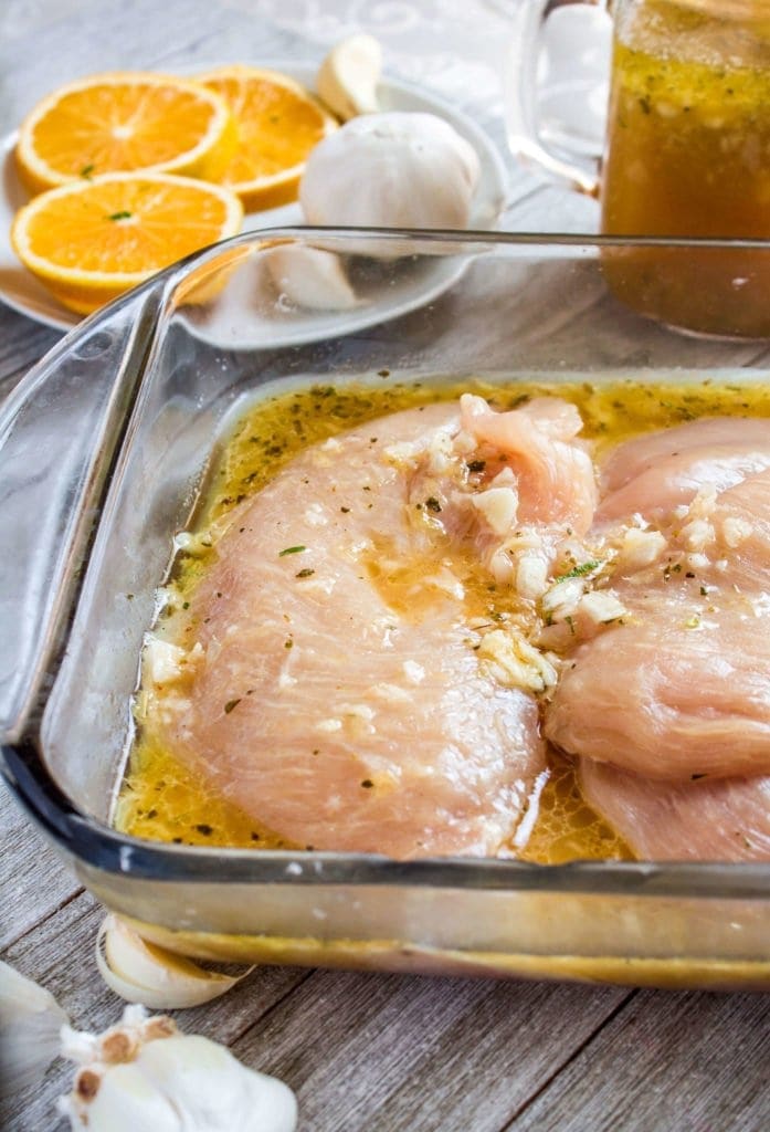 chicken is marinating in mojo criollo with garlic cloves and oranges