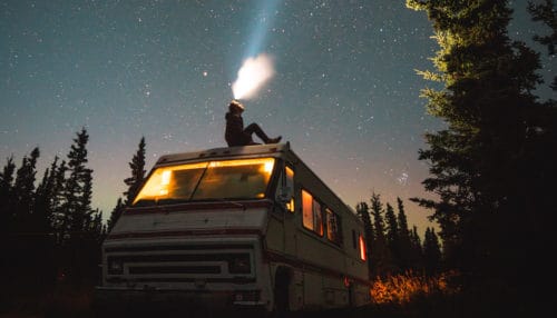 Rechargeable headlamps are great to have when camping because you won't need to worry about the batteries needing to be replaced. Person sitting on top of an RV looking up with a rechargeable headlamp