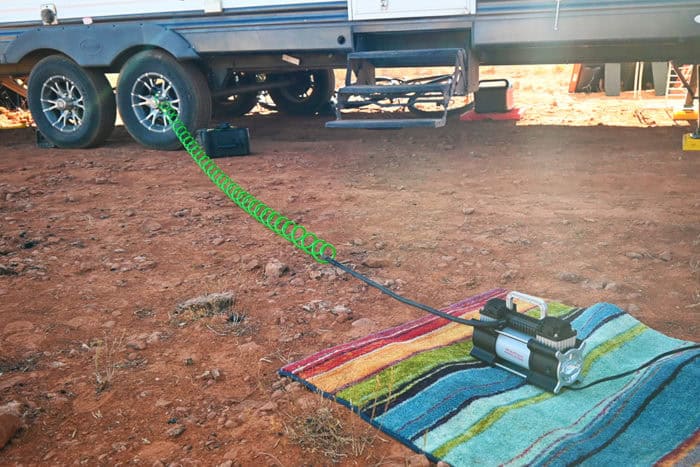 RV air compressors are great for maintaining the psi in camper tires even when out in the wilderness. rv air compressor and tire inflator connected to a truck and travel trailer