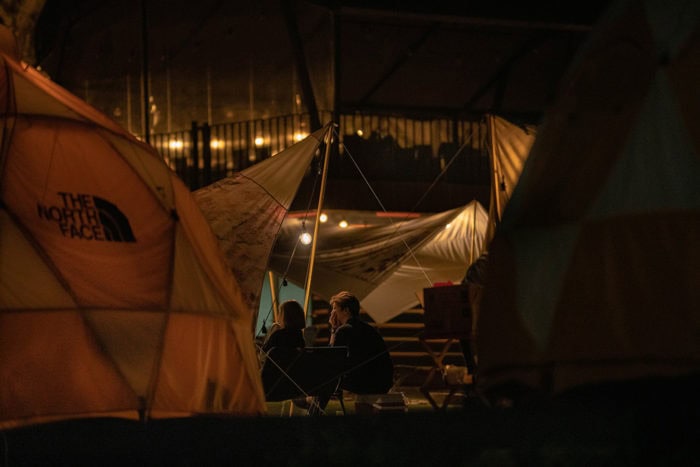 Oversized moon chairs are great for getting cozy on a cold evening. People sitting on camping chairs at a campsite (oversized moon chairs)