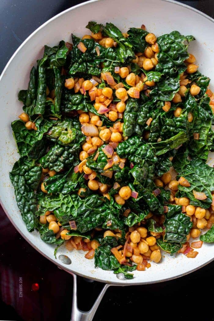 Kale chickpea stir fry in a skillet on the stovetop.