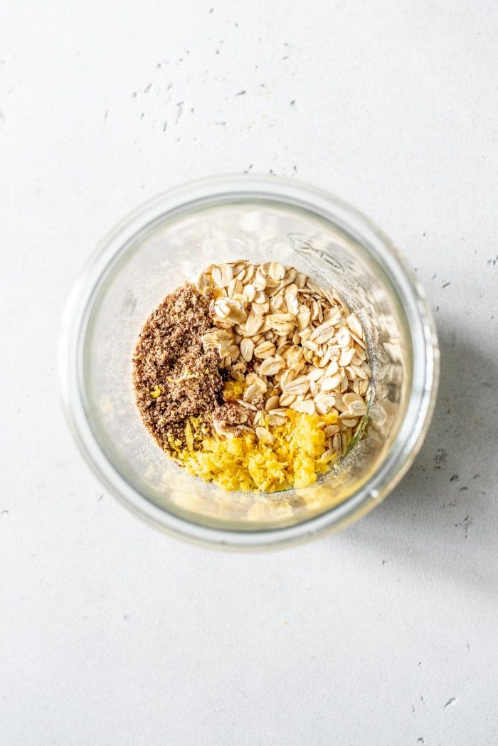 Ingredients for blueberry muffin overnight oats in a glass jar.