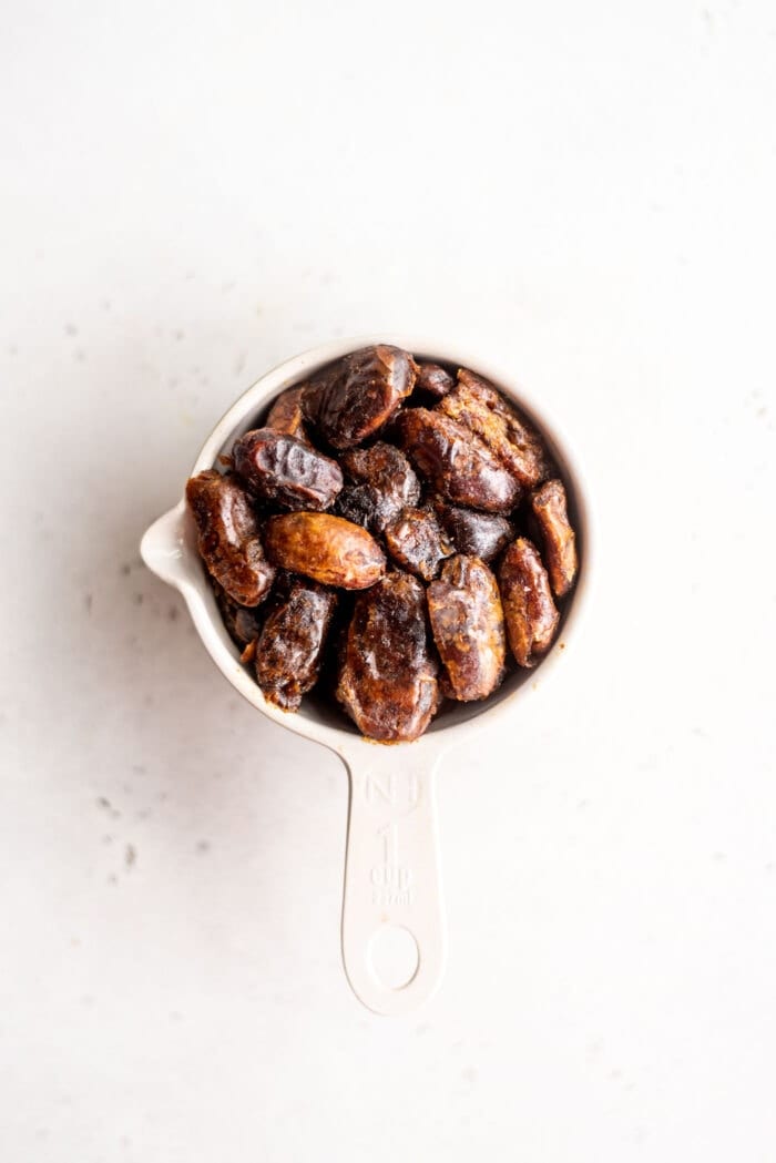 Pitted dates packed into a measuring cup.