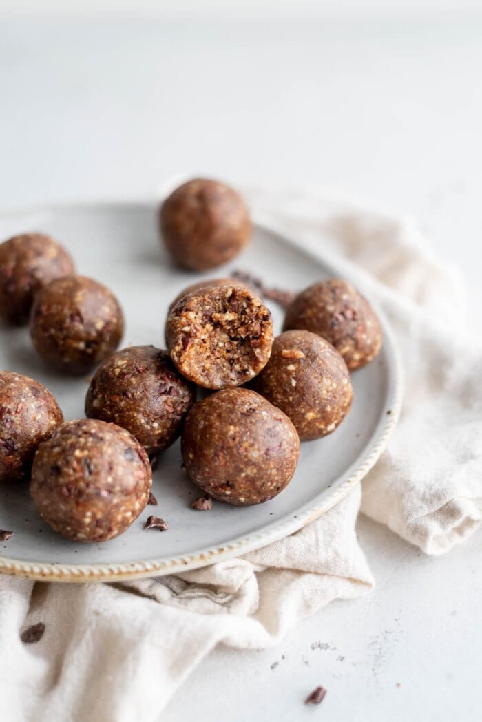A hazelnut energy ball with a bite taken out of it sitting on a small plate.