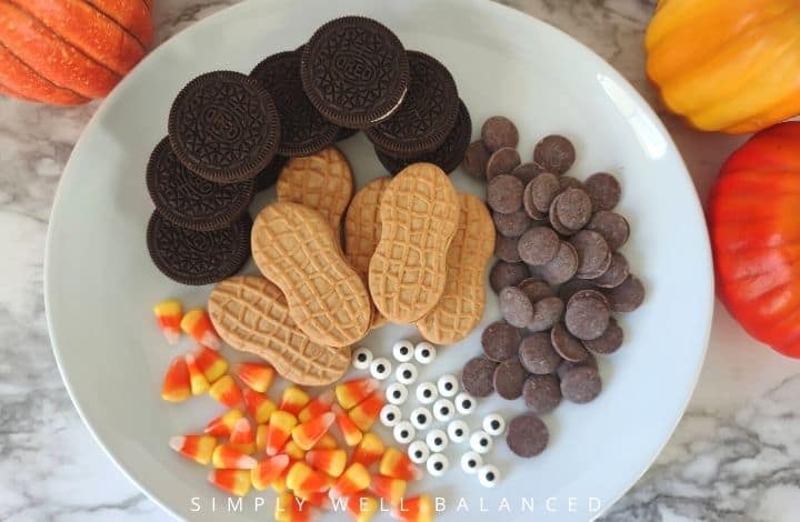 Ingredients for Nutter Butter Turkey Cookies. Nutter butters, oreos, candy corn, candy eyes and candy melts on a plate.