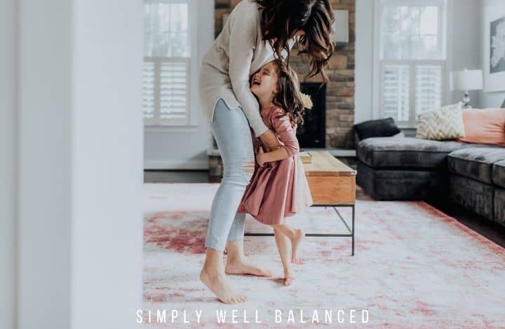 Mother and daughter dancing in the living room.