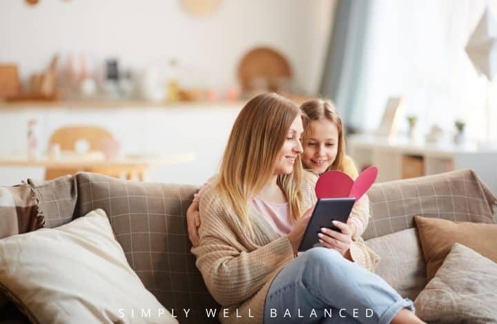 Mother and daughter reading a book and looking at Valentine's: