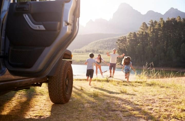 Family stopping to play at a pond on a road trip