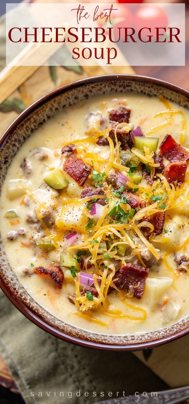 A closeup of a bowl of cheeseburger soup garnished with bacon and pickles
