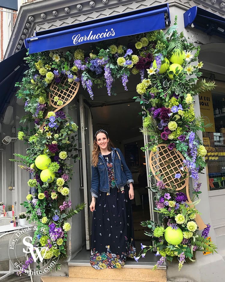 Sisley White at Carluccio's in Wimbledon Village who have a beautiful flower arch filled with over size tennis balls and rackets. In the Wimbledon purple and green colours.