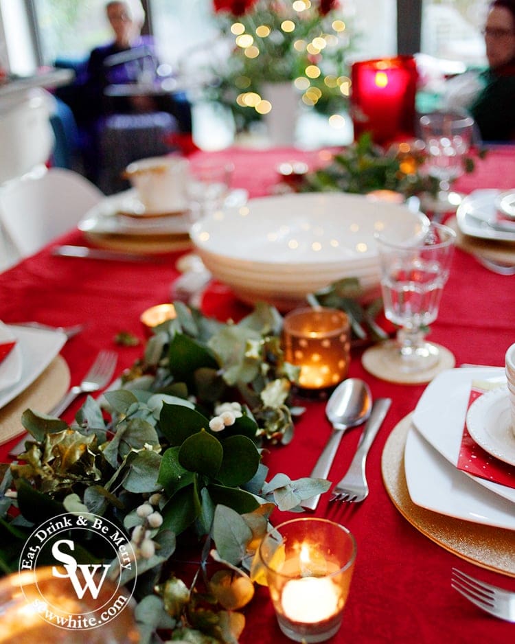 Red Gold and Nature Christmas Table using real foliage and candles on a red table cloth.