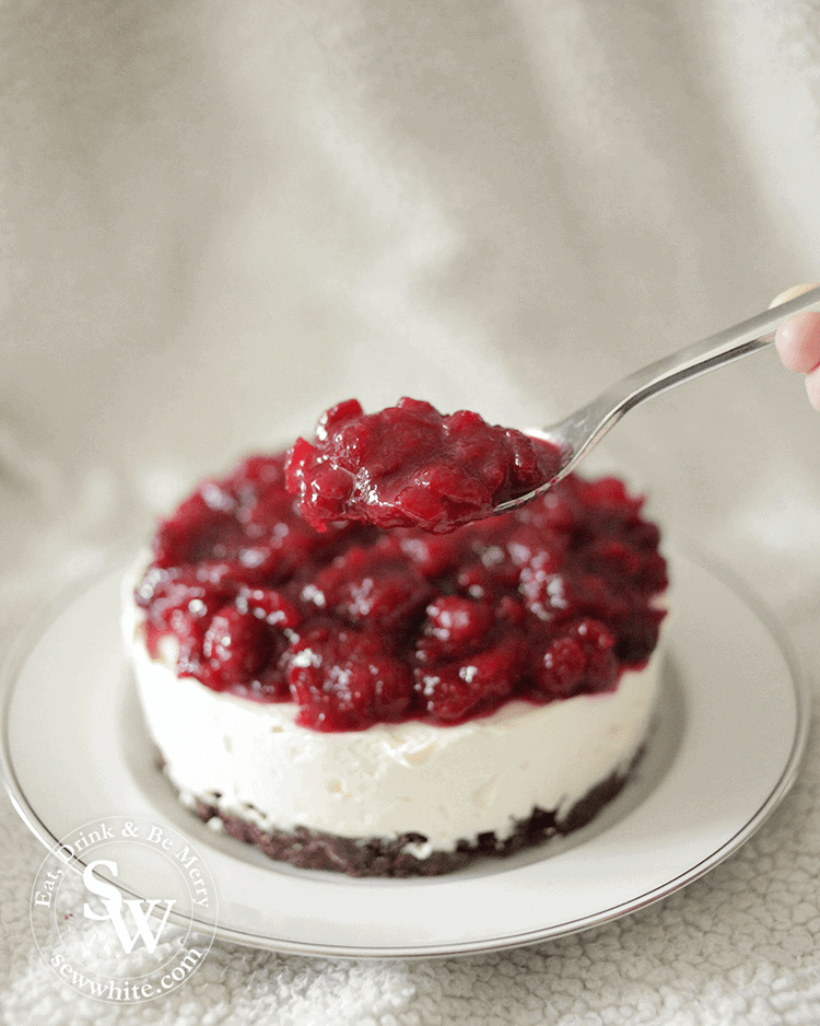 spooning on the orange and cranberry compote on to the cheesecake