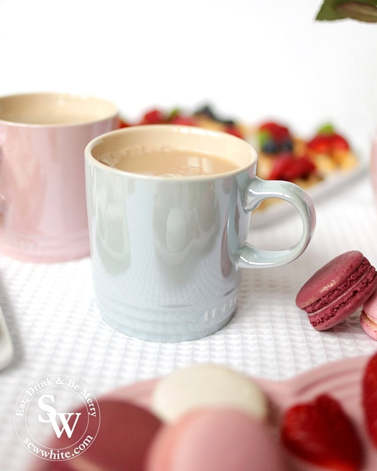 A cup of tea in the Le cureset stoneware glace collection mug served with macarons.