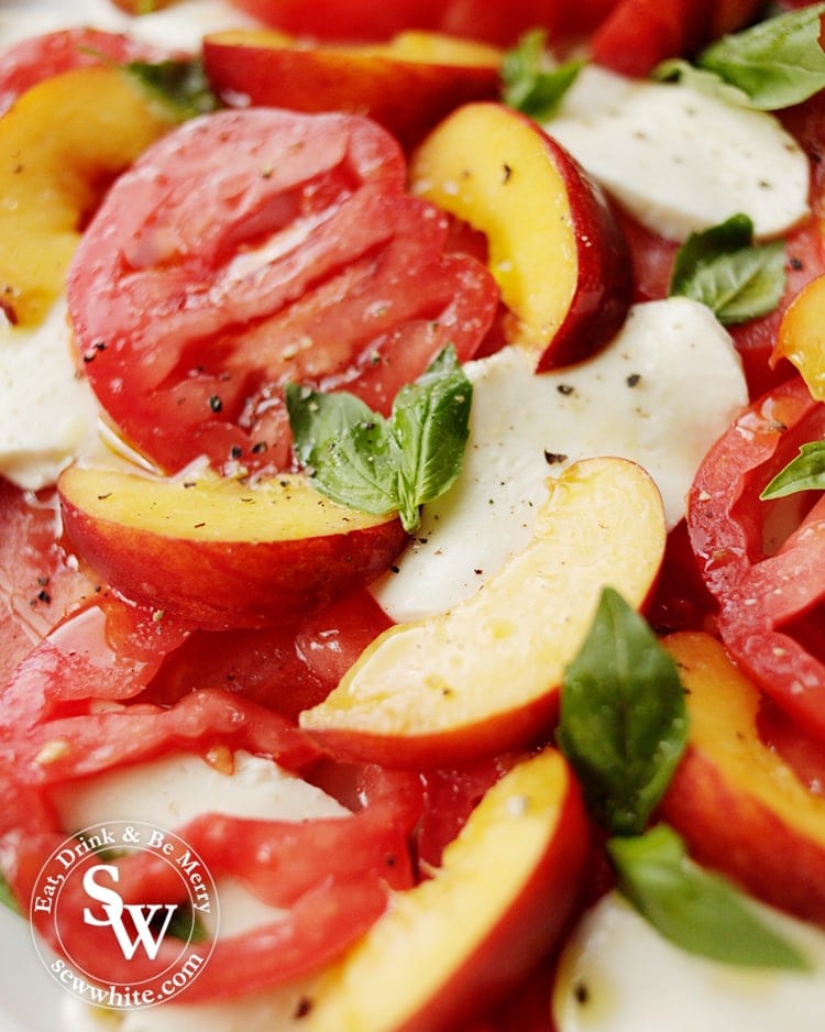 slices of red heirloom tomatoes in a peach summer salad with mozzarella.