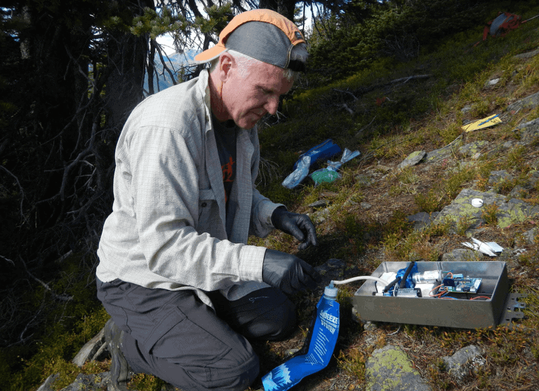 Robert Long prepares an automated scent dispenser meant to attract wolverines. The dispenser, which will be hung high in a tree above the snow line, will assist researchers in their effort to study wolverines in the winter when the Cascades are difficult to access. Photo by Paula MacKay.