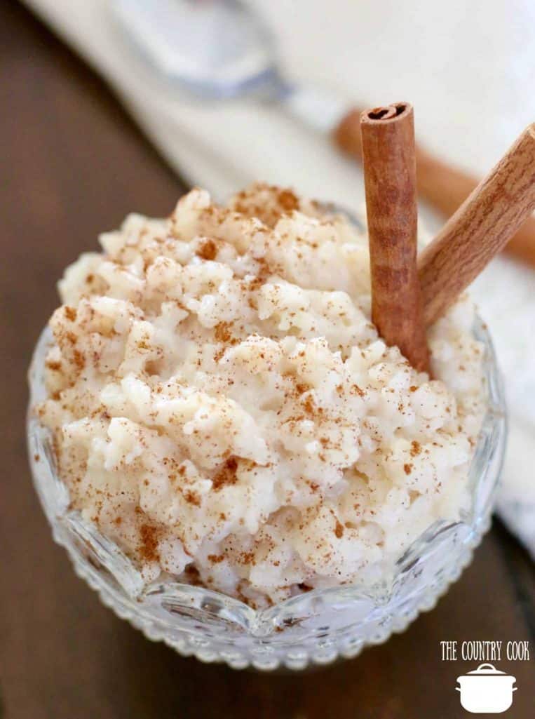 rice pudding in a decorative clear glass dessert bowl with two cinnamon sticks