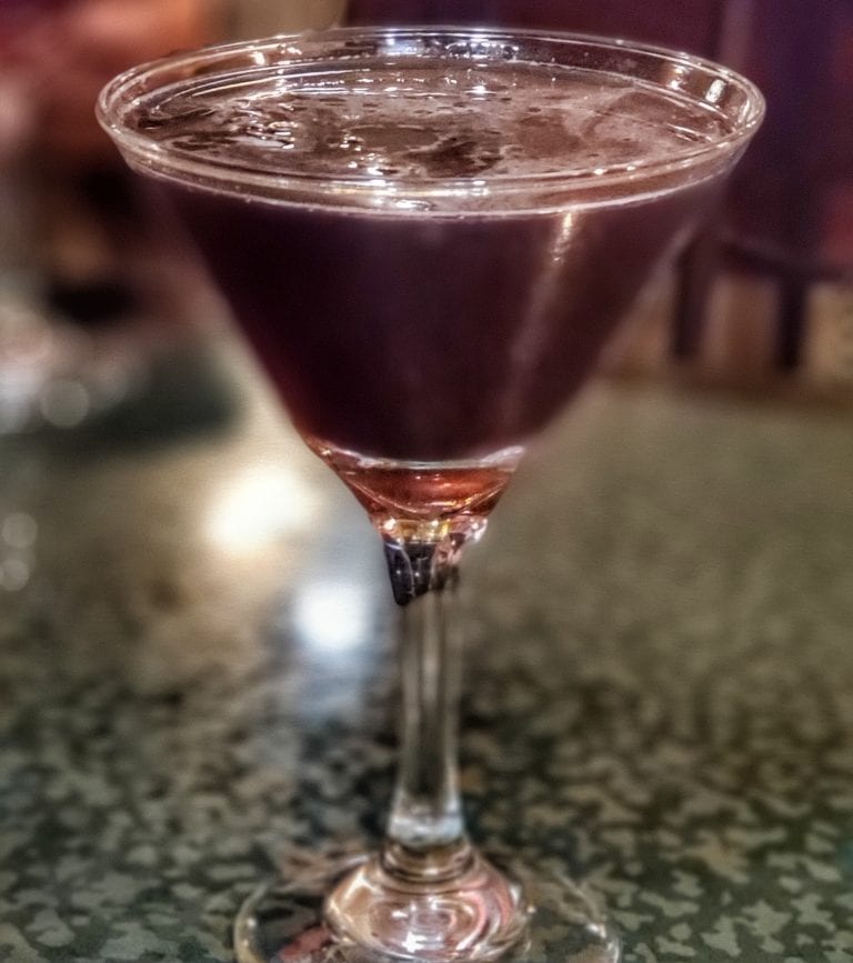 Purple-black cocktail in Martini glass